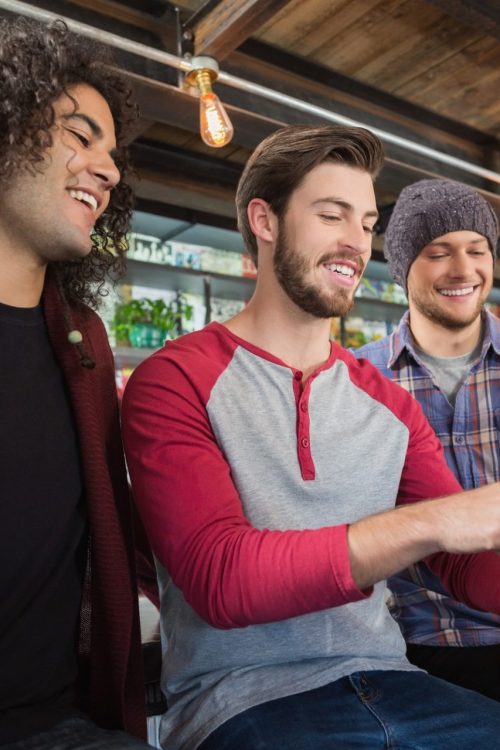 Happy male friends using digital tablet in restaurant
